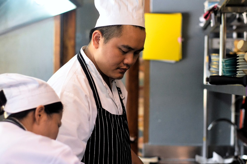 Bo.Lan alumnus Chef Pui Kritsanarak plating dishes in the Err kitchen. .