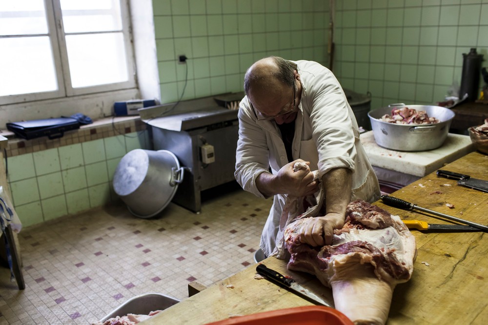 15/01/2014 - France / Aquitaine - La decoupe de la carcasse est une affaire de specialiste. ici le boucher desosse le futur jambon qui ira rejoindre le sechoir pendant plusieurs mois. Le tue-cochon, ou fete du cochon, est une tradition des campagnes francaises, qui correspond a l'abattage, la decoupe et la cuisine de la viande de porc. Autrefois moment important de la vie rural, cette tradition se perd aujourd'hui. Simon Lambert / Haytham Pictures 15/01/2014 - France / Aquitaine - Kill the pig - Slicing the carcass is alo a matter of specialist. The butcher here prepares the ham before it will be dried several months. Simon Lambert / Haytham Pictures